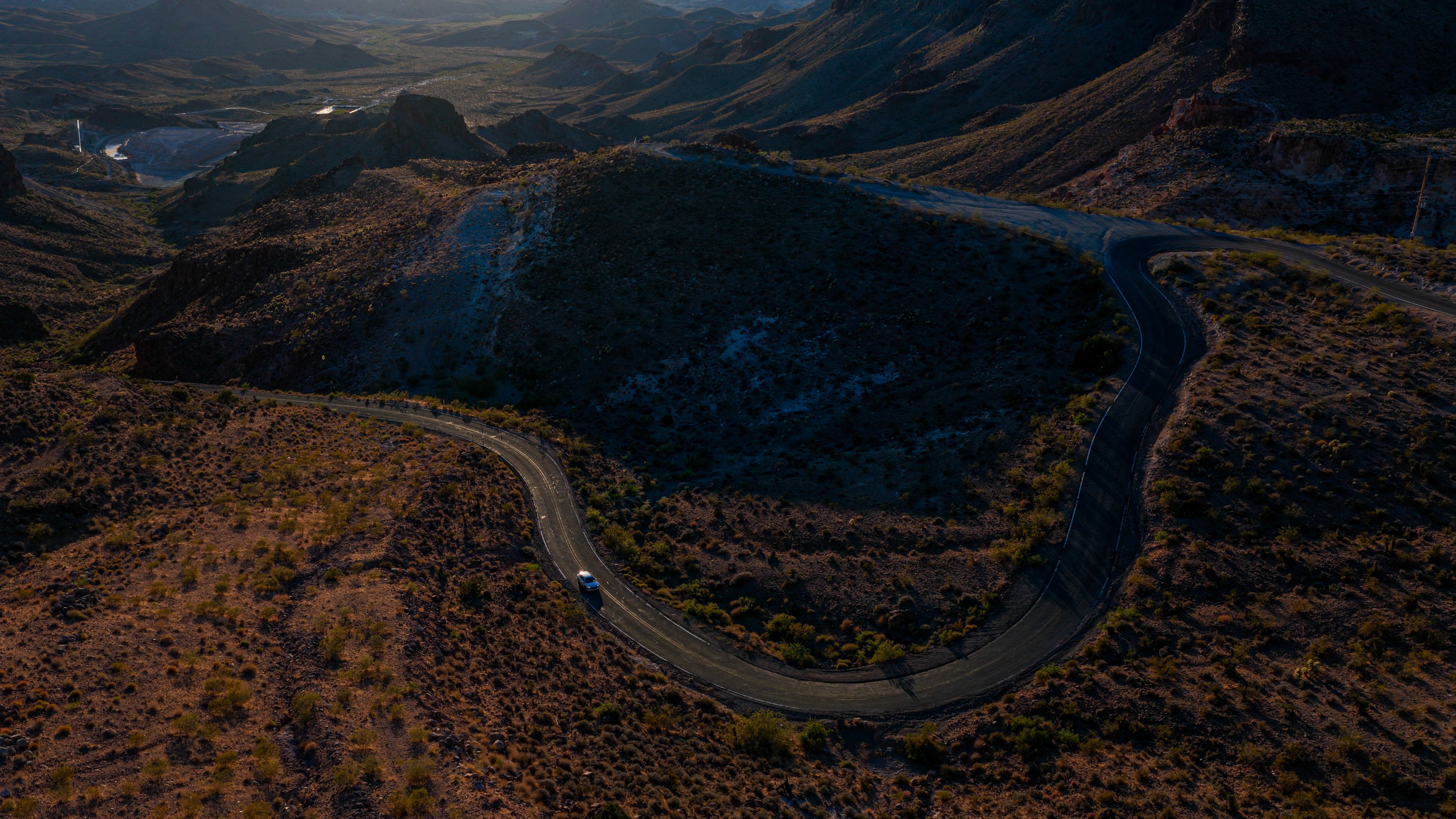 A winding mountain road seen from above at golden hour — a GEO strategy is a route, not a destination