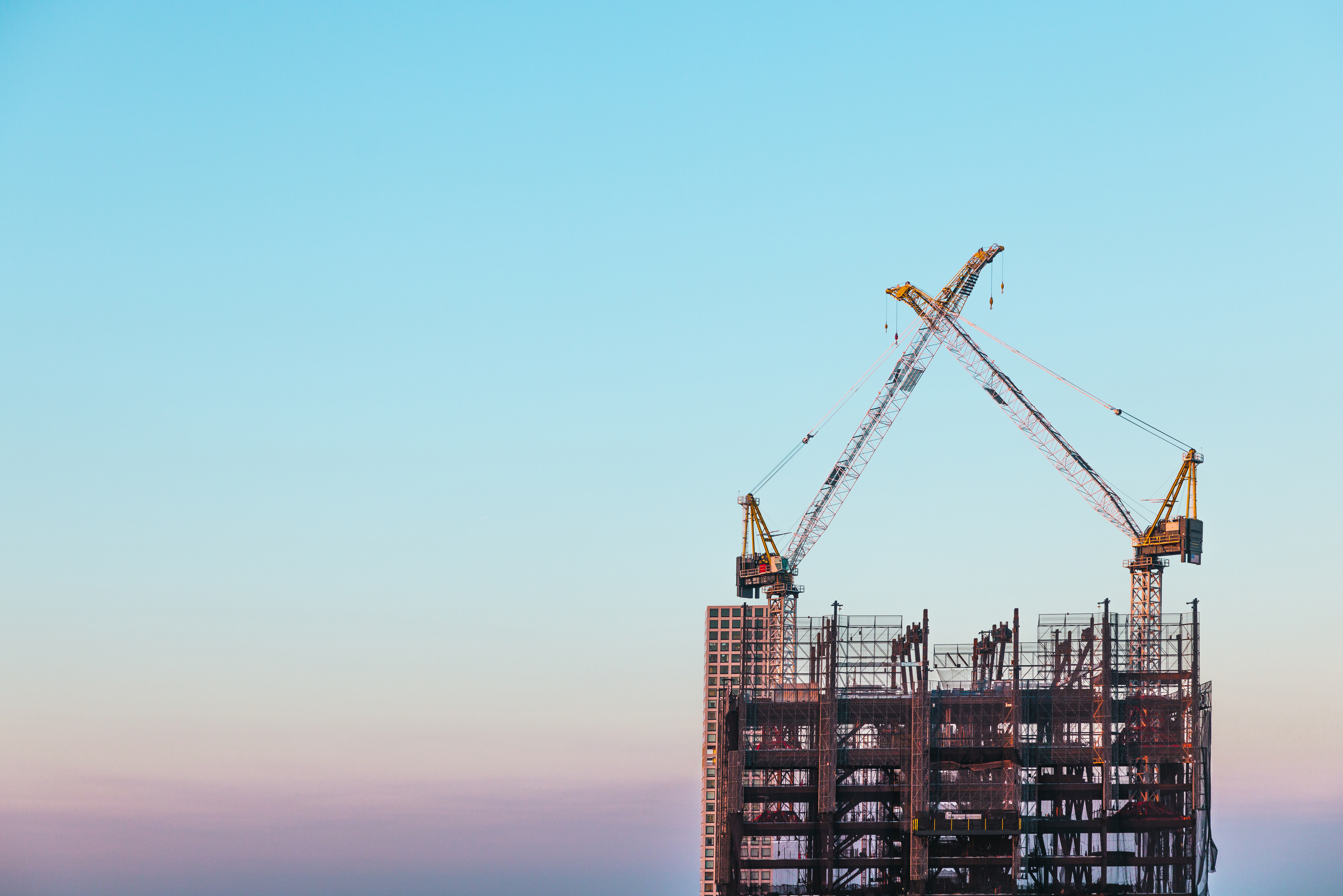 Construction cranes over a skyline at dawn — new categories are being built while the market watches